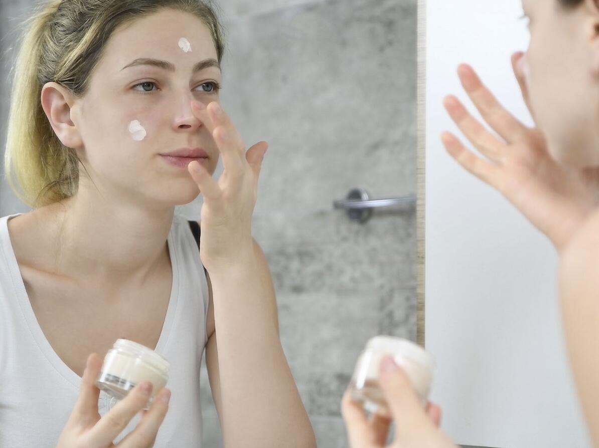 Kvinde smører creme i ansigtet