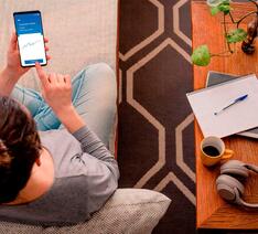 Kvinde sidder i sofa og investerer selv sine penge.