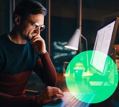 Mand kigger sin pensionsordninger igennem på computer i mørket