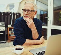 Mand med computer og kop kaffe