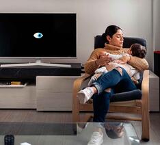 Kvinde med barn i lænestol ved siden af et smart-tv