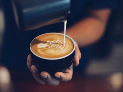 Person har brugt sin mælkeskummer til at skumme mælk til kaffen