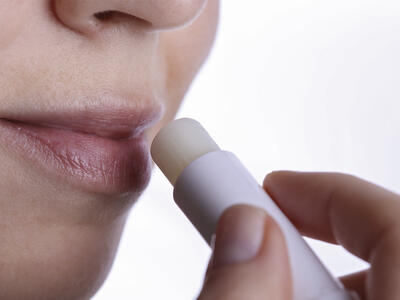 Kvinde smører læbepomade på læberne