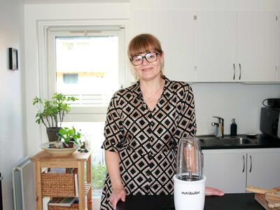 Halvnær af Katja, der står i sit køkken med en blender